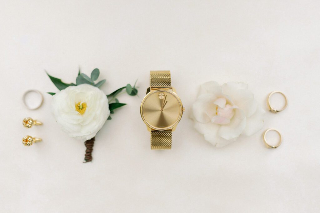 Gold watch, wedding rings, boutonniere, and flowers