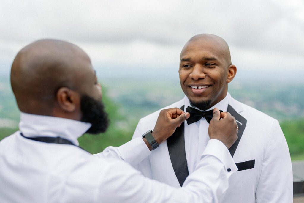 Groomsmen helping groom adjust bowtie before wedding ceremony