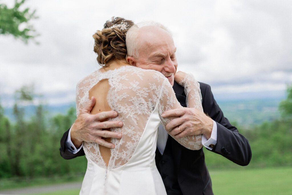 Bride hugging father after first look before rainy mountaintop wedding 