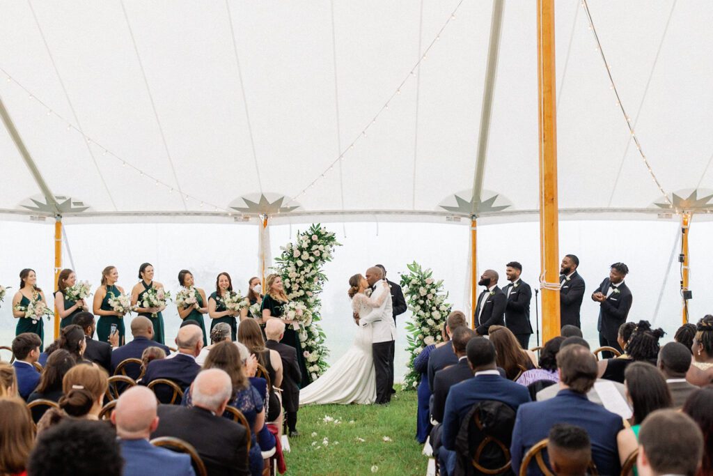 Bride and groom embrace and kiss after wedding ceremony