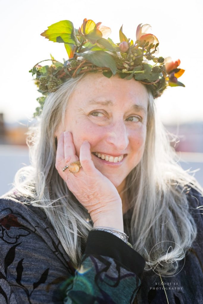 Lynne with hand on face wearing a floral crown celebrating International Women's Day