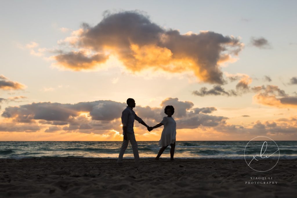 man and woman walking hand in hand down the miami beach during engagement session