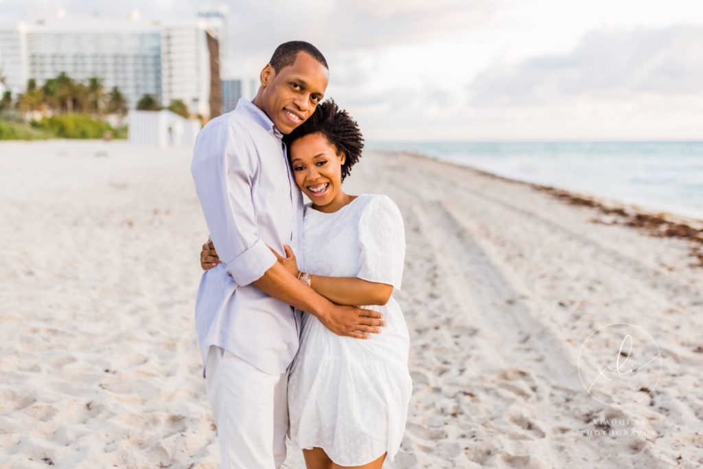 Newly engaged couple standing together hugging on Miami Beach during engagements