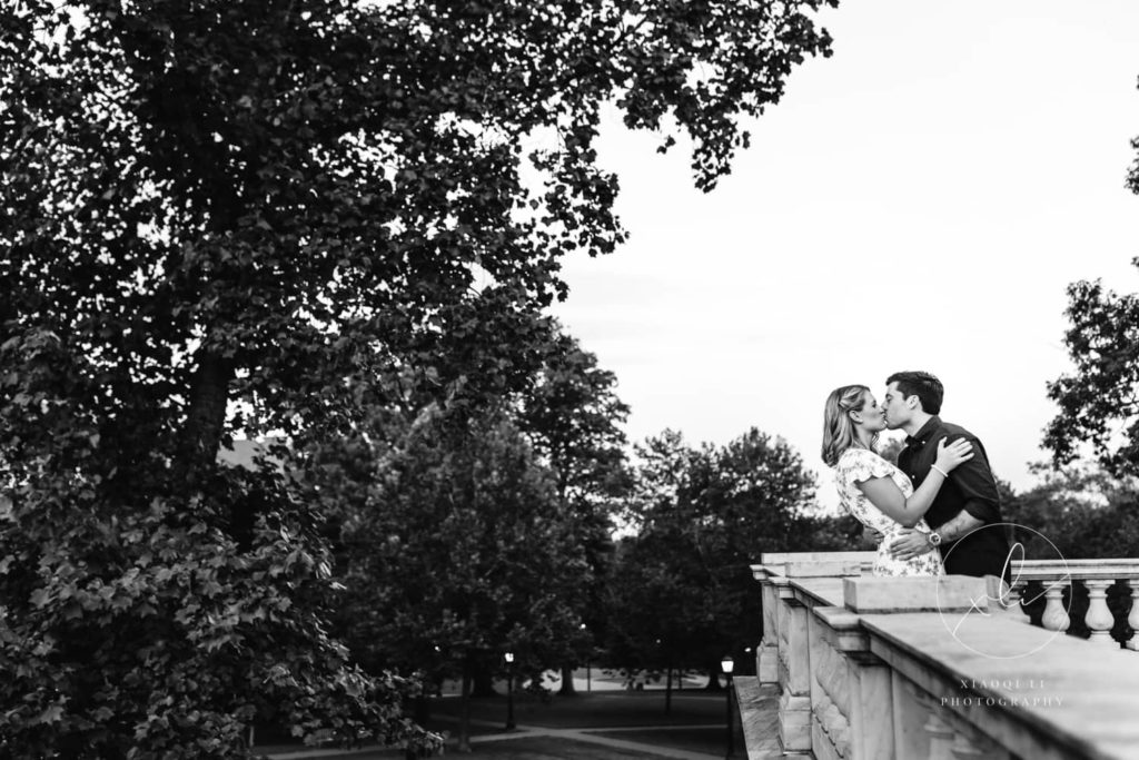 newly engaged couple kissing on bridge