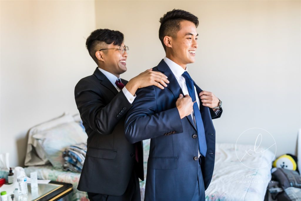 father helping son prepare for wedding day by putting on suit coat before richmond wedding