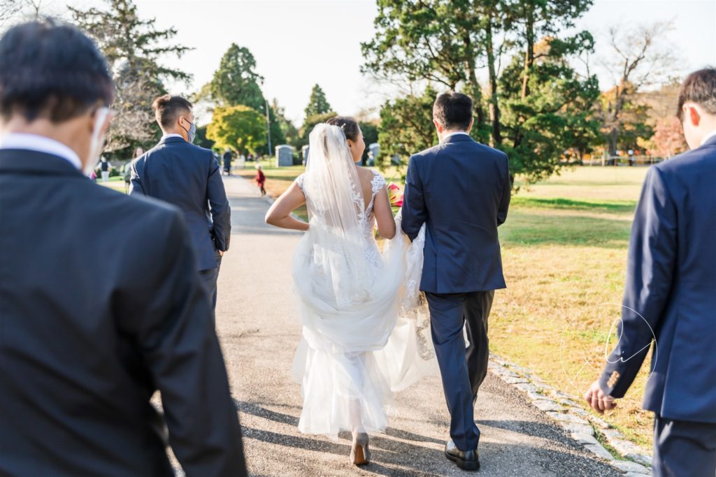 Couple walking together on wedding day while man holds woman's dress