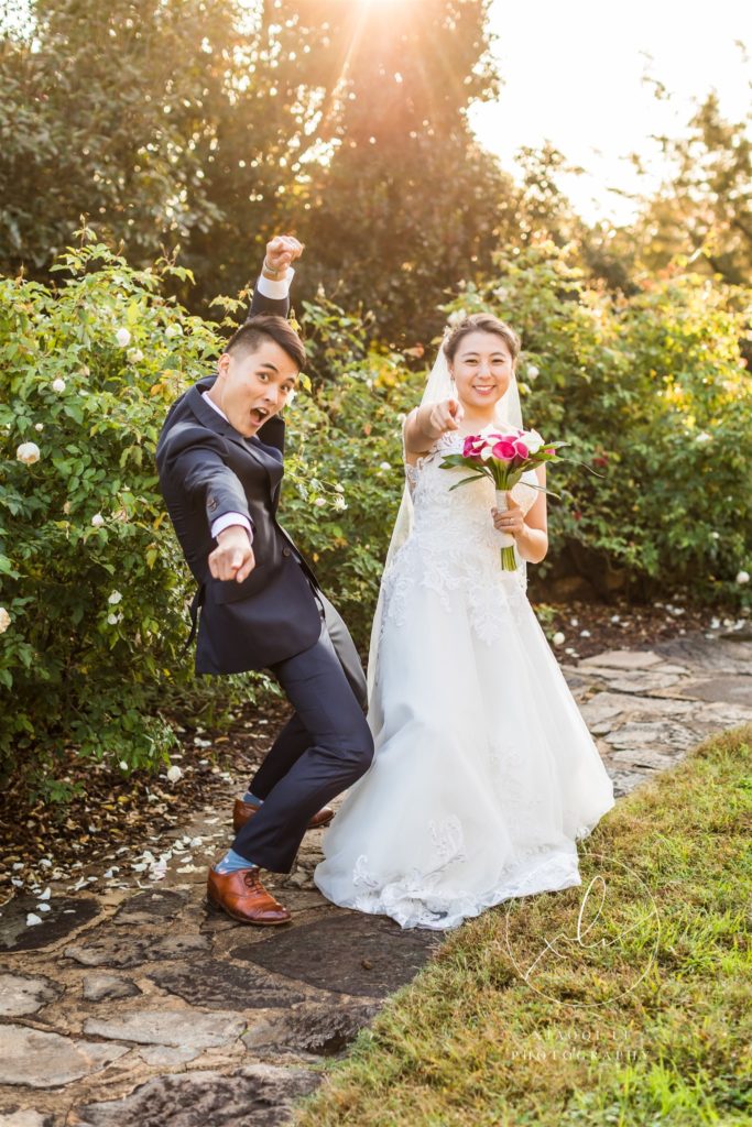 Bride and groom celebrating recent marriage by pointing and smiling at camera
