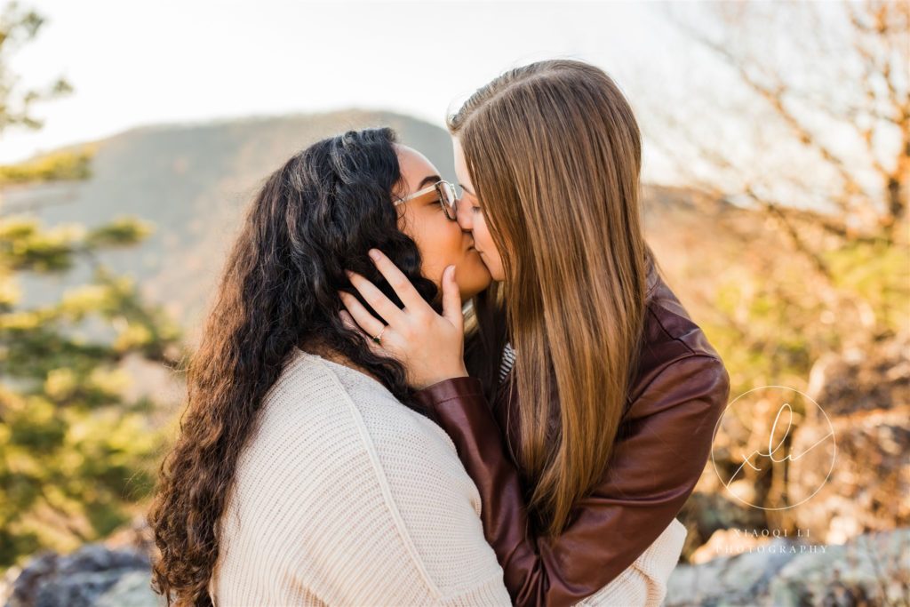 Emily and Sophie kissing during engagement session at chick's beach and blackrock summit