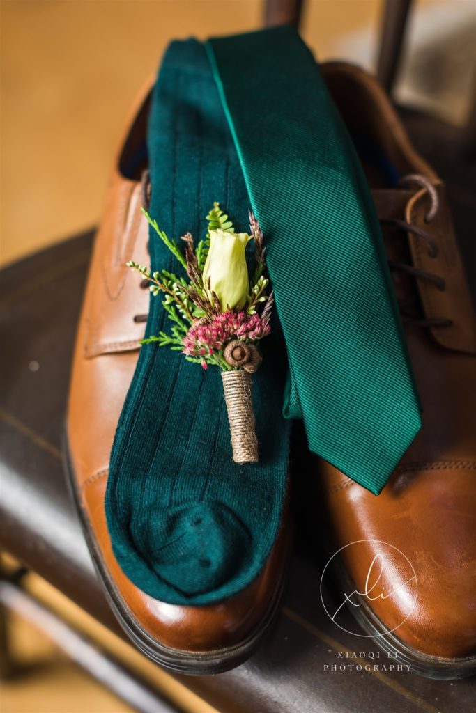 detail shot of wedding attire brown shoes, green tie, and boutonniere 