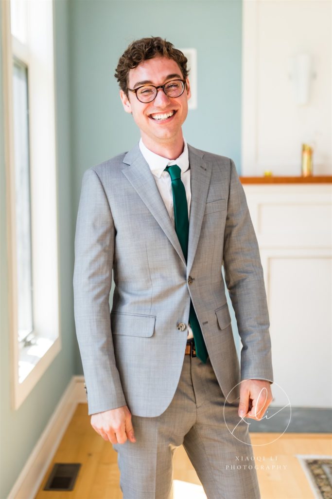 Man smiling on wedding day wearing grey suit and emerald green tie