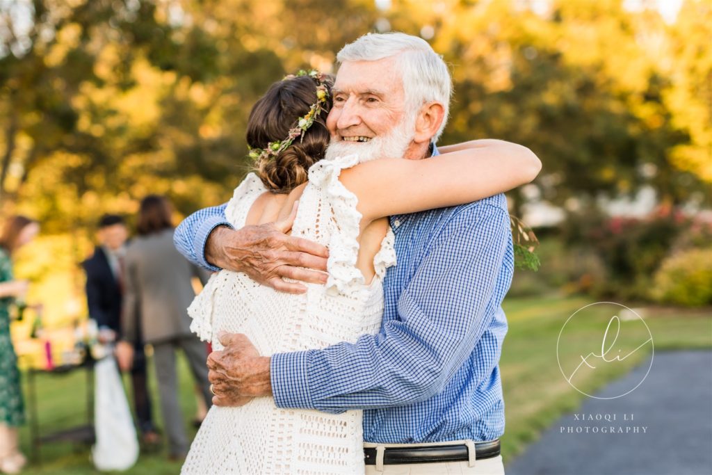 Bride hugging grandfather after fall backyard wedding