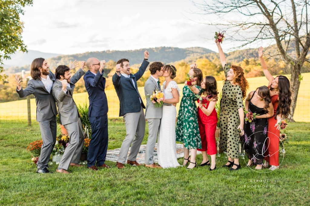 wedding party celebrating recent marriage while couple kisses