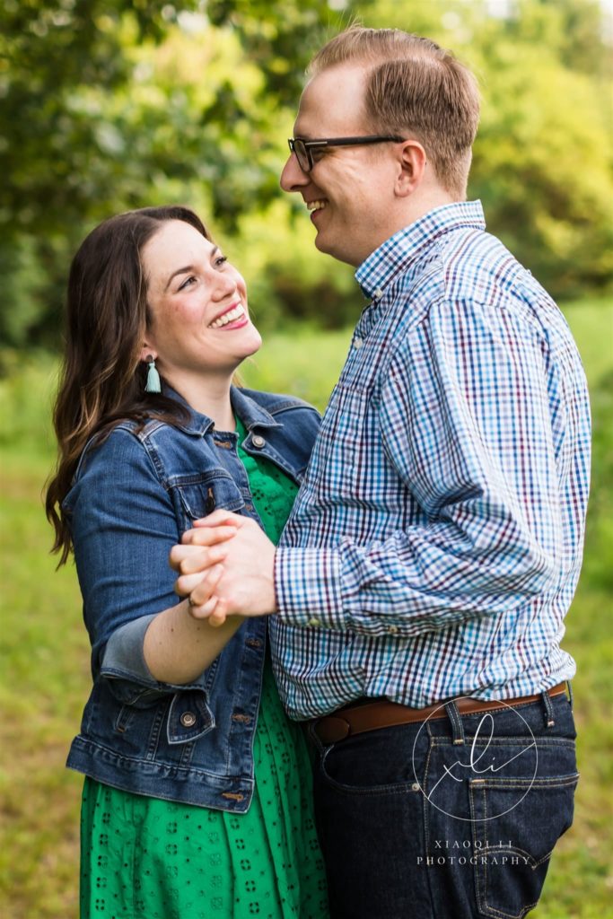 man and woman holding hands and dancing outdoors in ivy creek natural area engagement session
