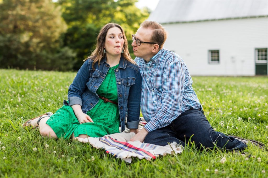 couple sitting on blanket in grass making silly faces together