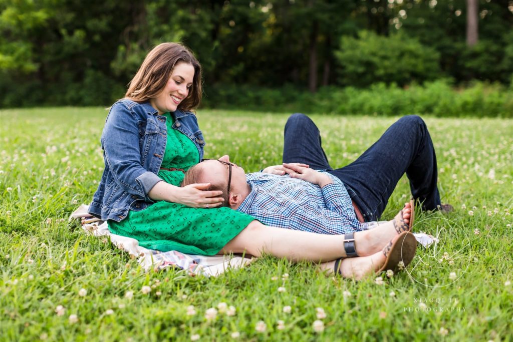man resting head in woman's lap talking during engagement session