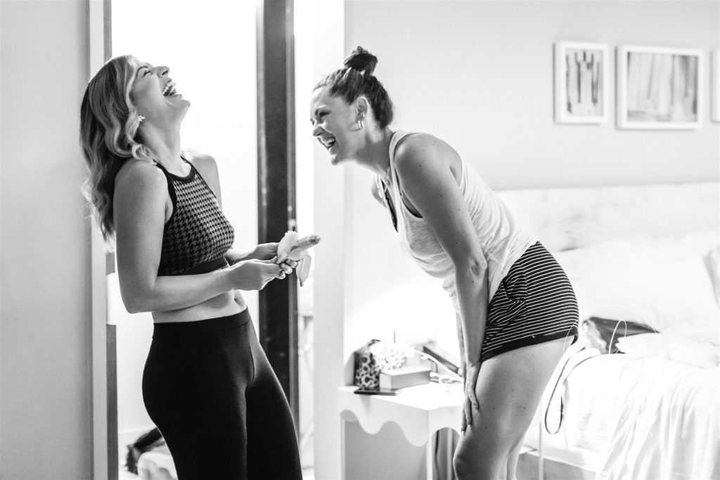 two women laughing while getting ready on wedding day in Richmond