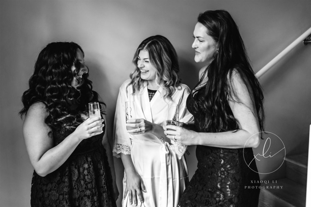 Bride laughing with friends on wedding day in Richmond Virginia wearing robes while getting ready together