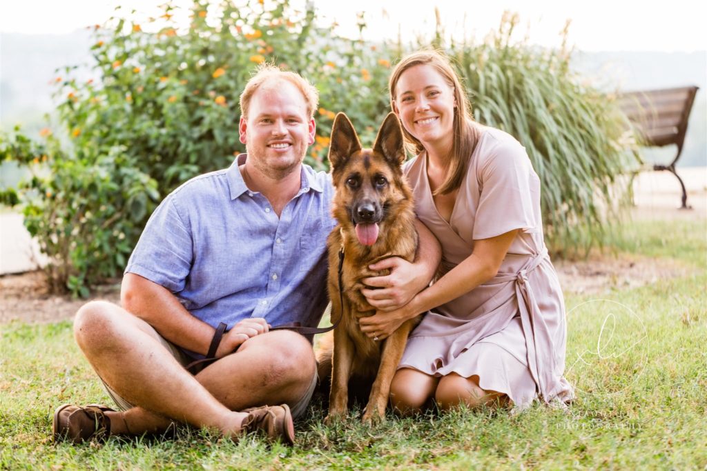 newly engaged couple sitting on ground with dog Stella during session
