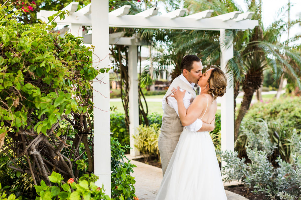 Newly married couple kissing under pergola in Bahamas