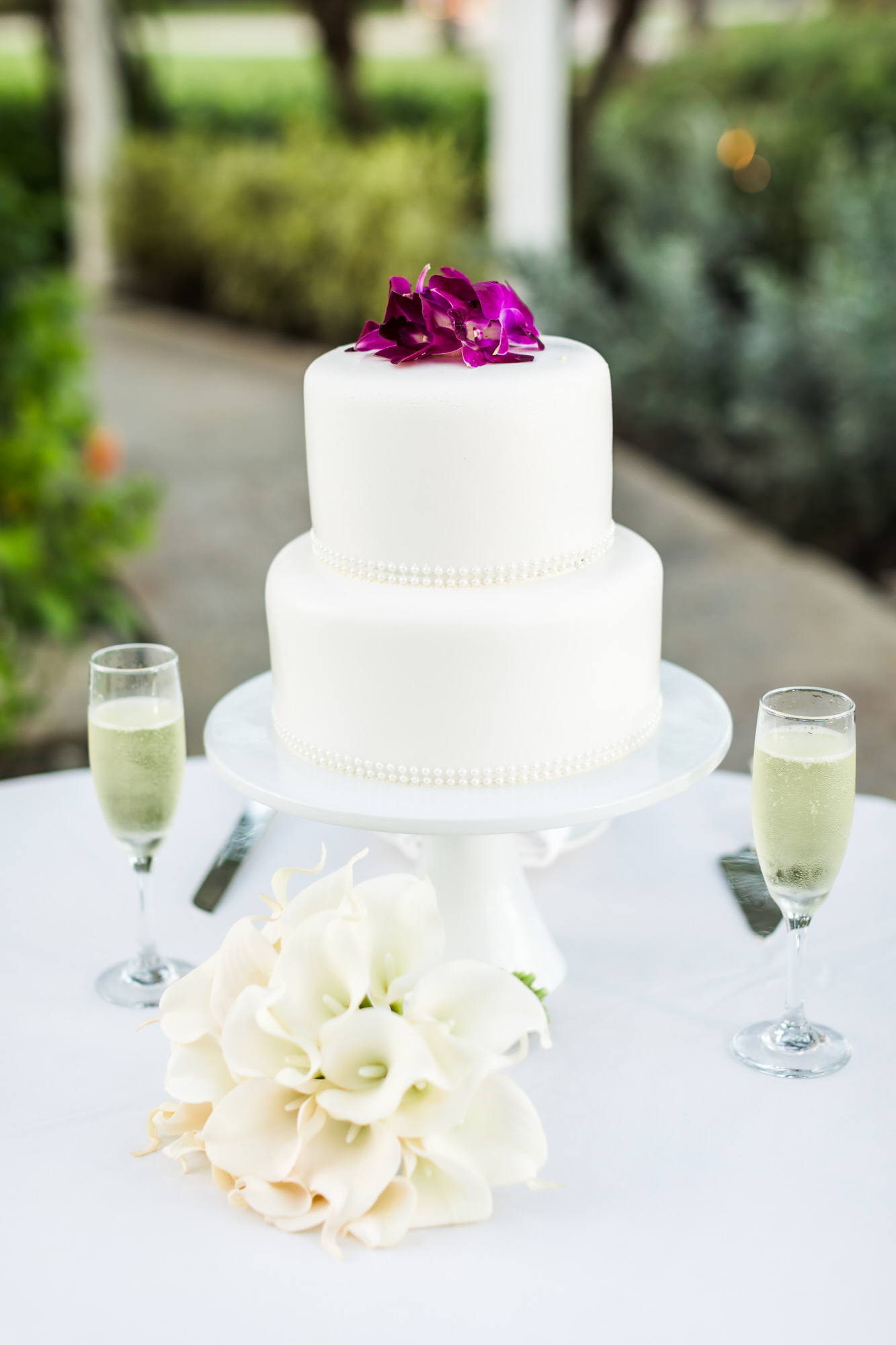 white wedding cake with purple flowers and wedding bouquet