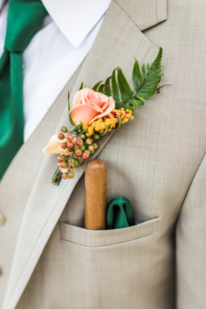 close up of groom's grey suit, boutonnière and cigar