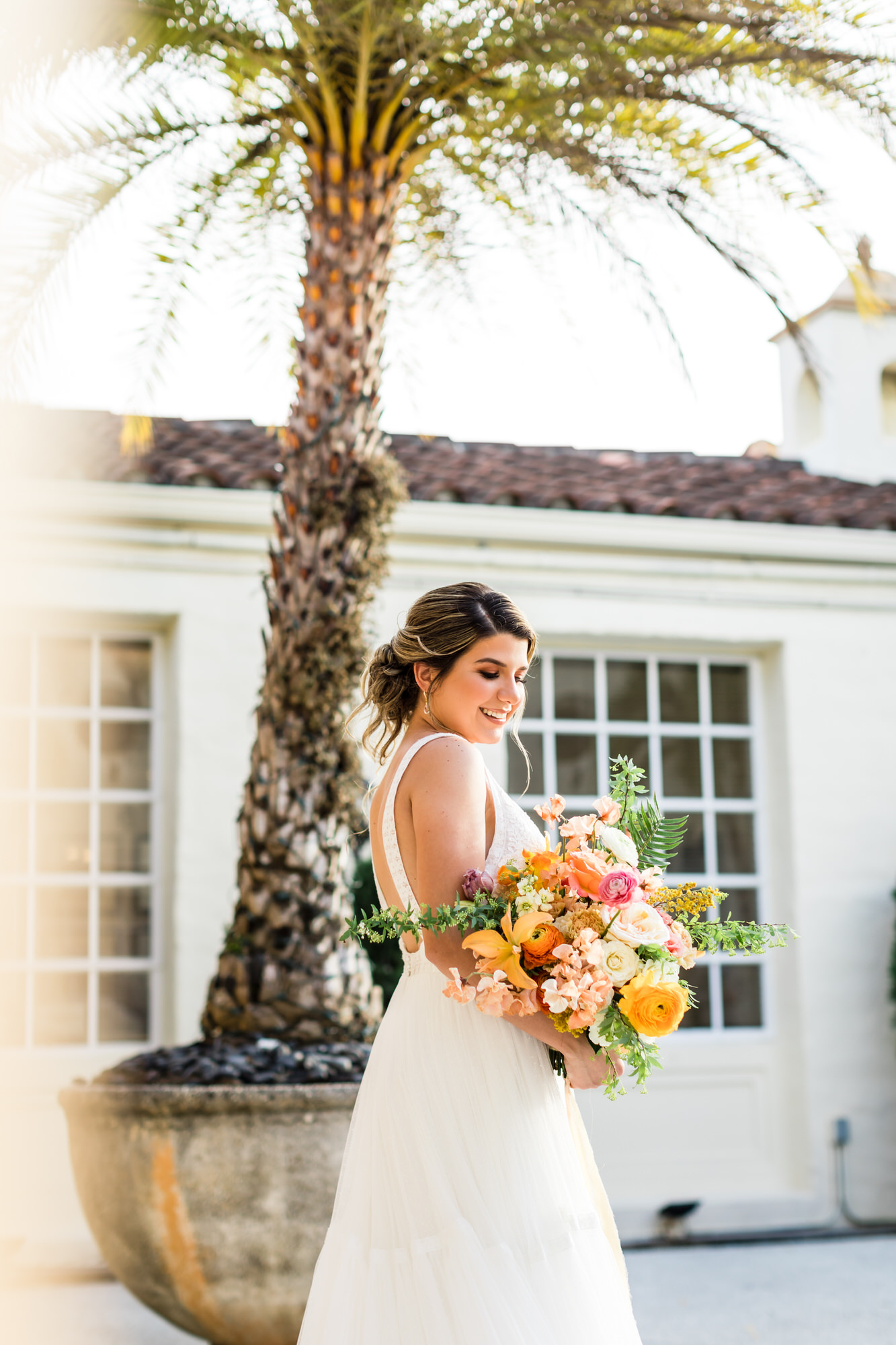 bride wearing strapless wedding gown holding brightly colored bouquet at Cuban inspired wedding