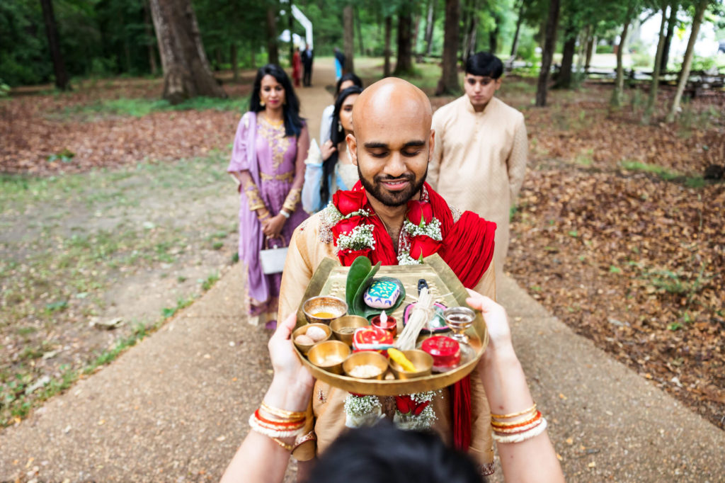 woman giving man plate of ceremonial objects during wedding ceremony