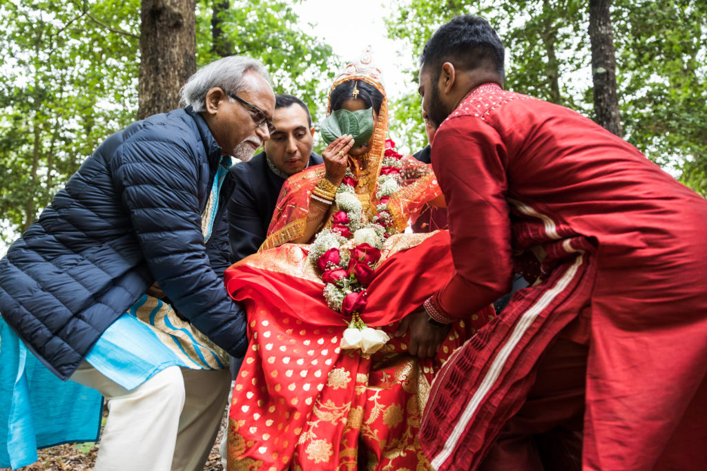 family and friends carrying bride to ceremony during hindu muslim interfaith wedding