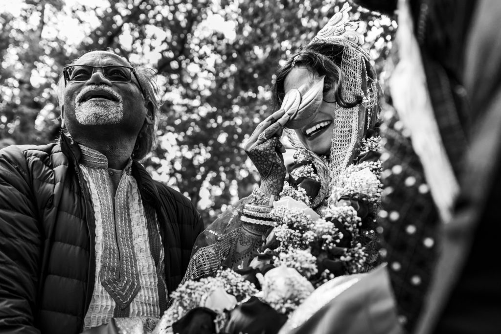 bride smiling and laughing as she is carried to alter to get married