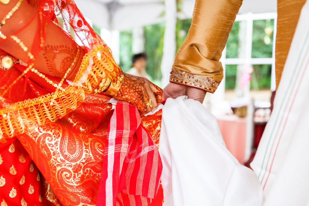 bride and groom holding hands while holding white cloth during ceremony
