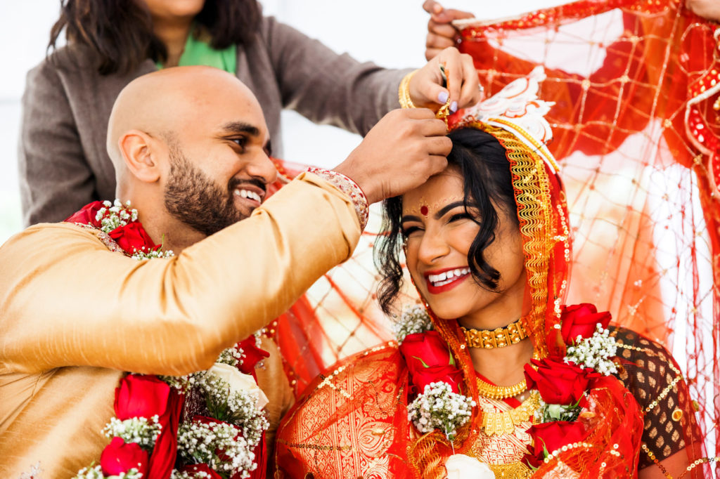groom placing object on bride's head during traditional wedding ceremony