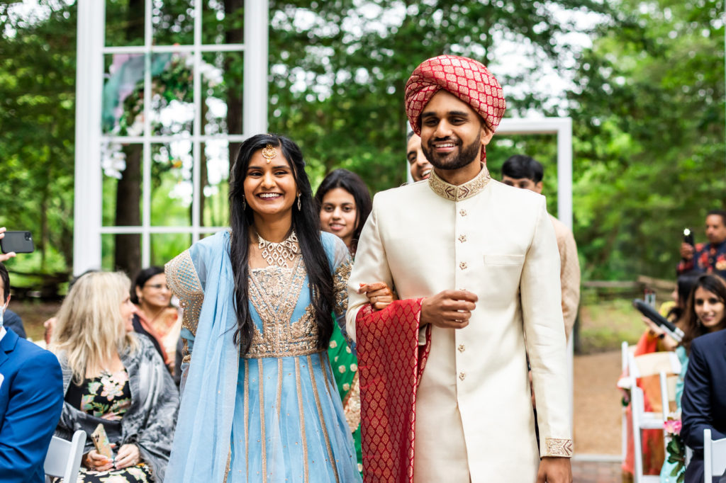 man and woman walking down the aisle during hindu muslim interfaith wedding