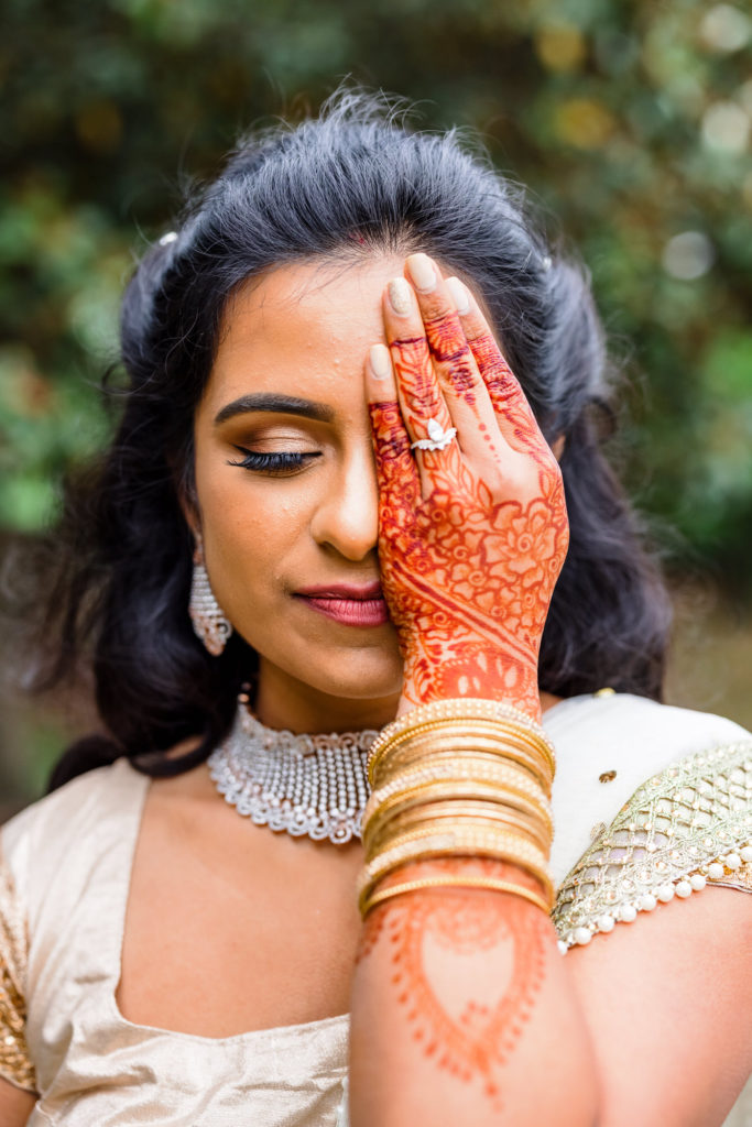 bride covering half of face with hand covered in beautiful artwork