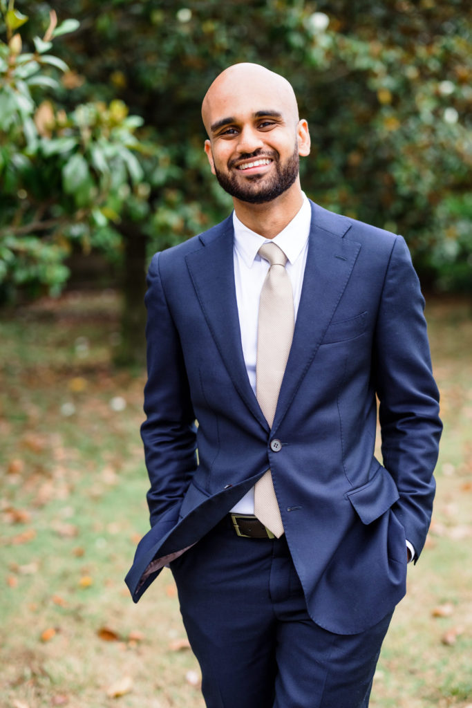 groom smiling and laughing at camera while wearing navy suit and grey tie
