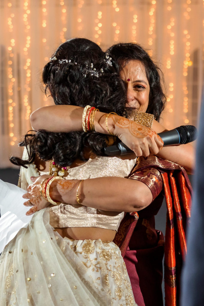 bride hugging family member after speech at wedding reception