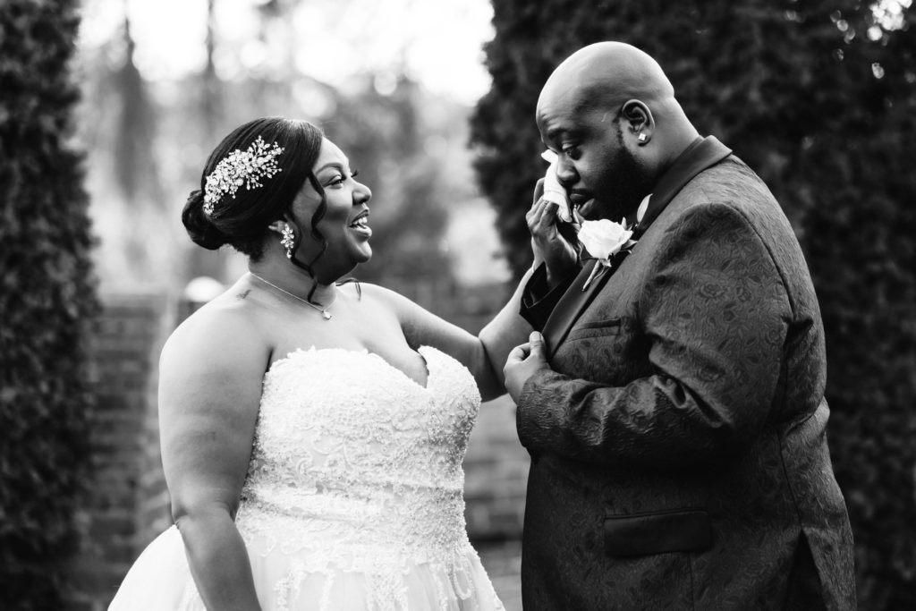 bride wiping groom's face after he teared up seeing her during their outdoor first look
