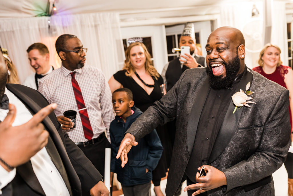 groom laughing and dancing with friends and family at new years eve mankin mansion wedding