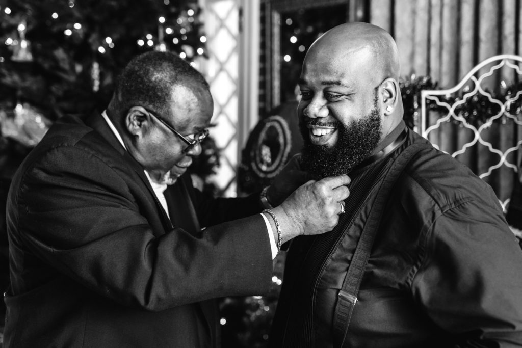groom getting bow tie on wedding day with help of father