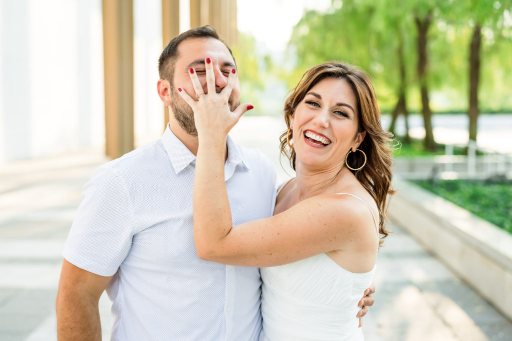 woman putting hand over man's face making silly face