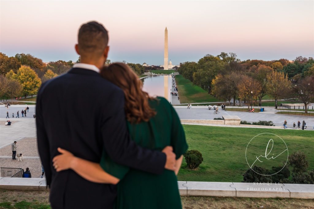 man and woman hugging and looking at memorials during fall DC engagement session
