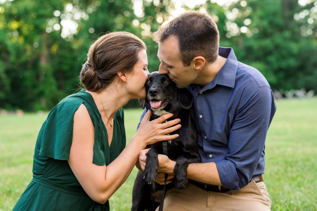 engaged couple hugging puppy and kissing dog, Rose during engagement session