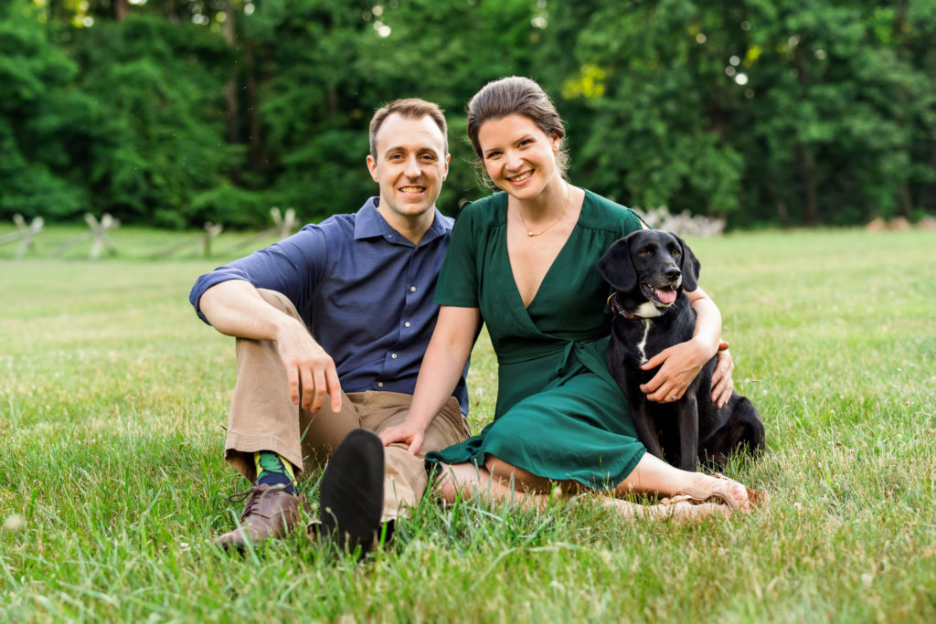 couple sitting on grass with dog, Rose during outdoor Virginia summer engagement session