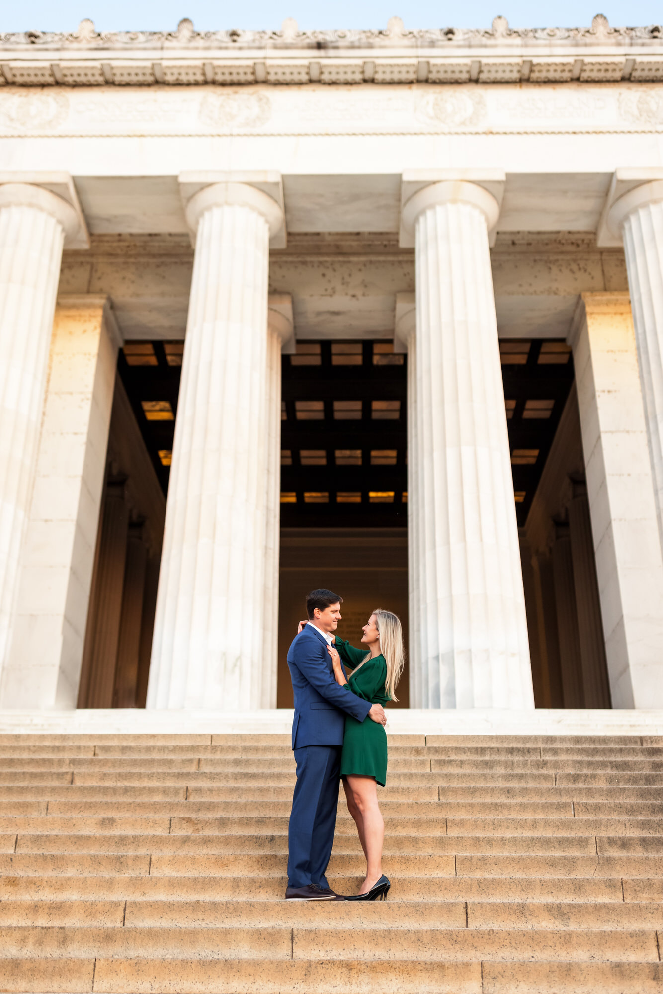 newly engaged couple standing on steps of lincoln memorial during sunrise engagement session