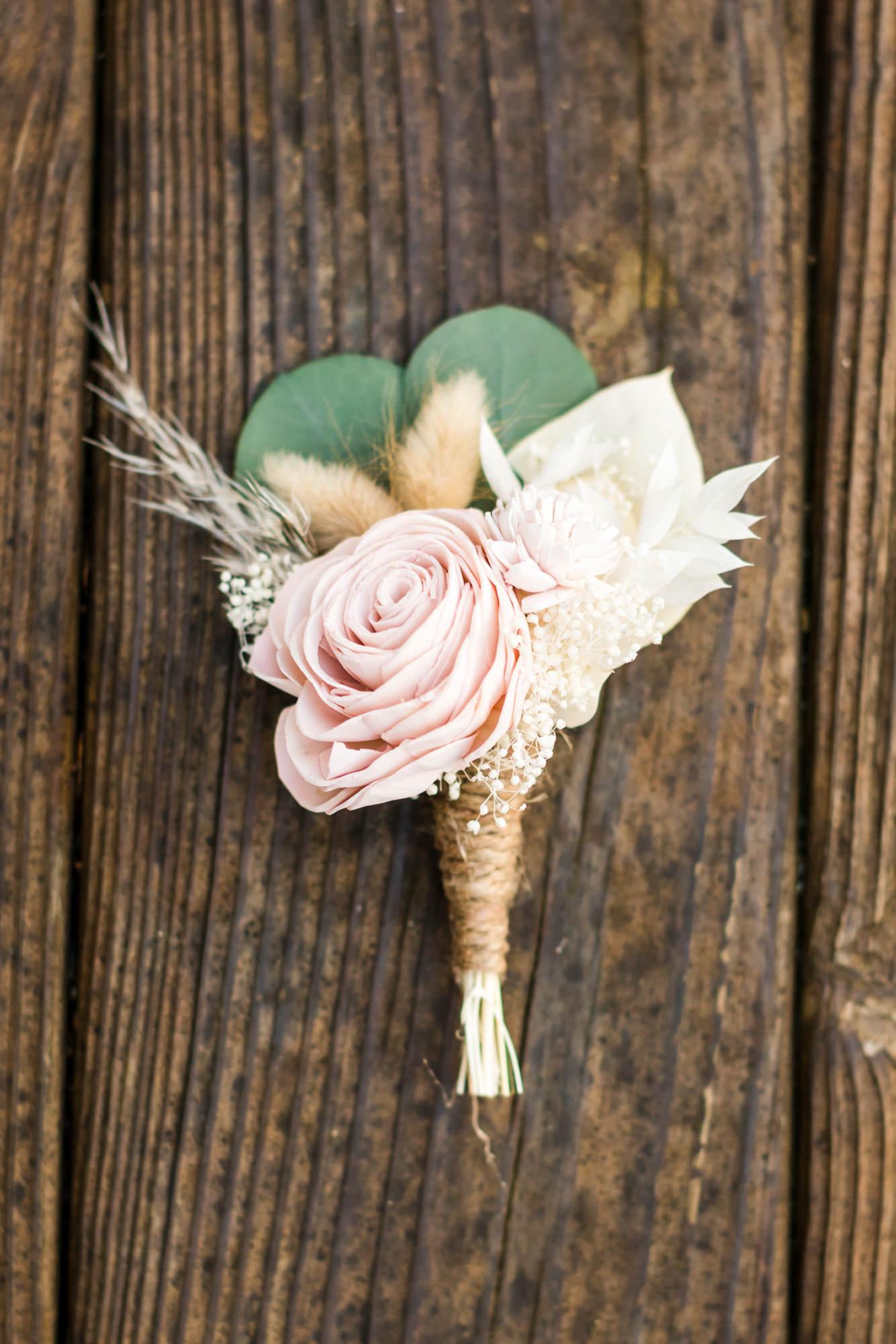 detail shot of woodland chic, groom's pink rose, greenery, and burlap boutonniere at airbnb wedding
