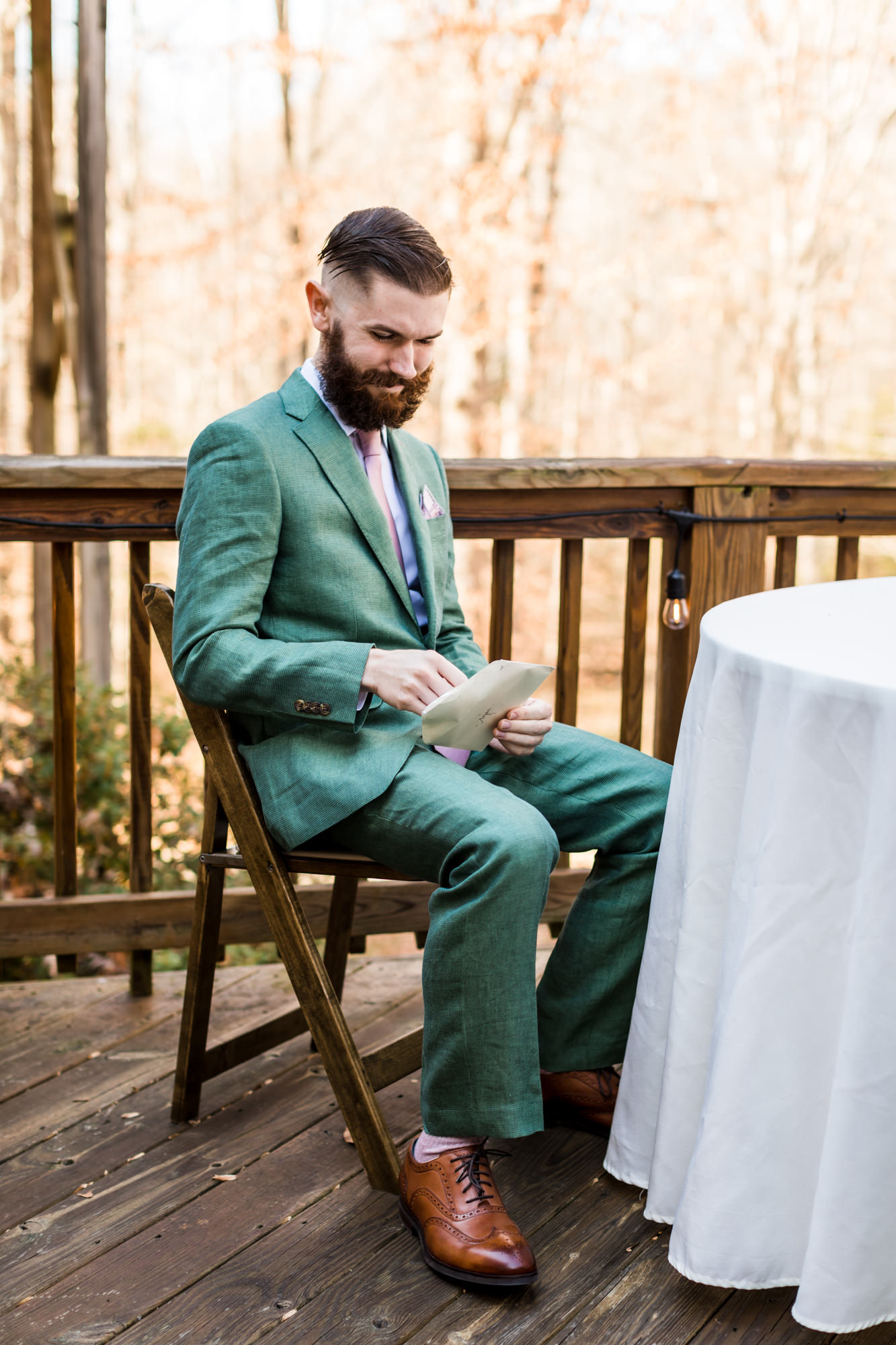 groom reading letter from bride on airbnb wedding day in Charlottesville wearing green plaid suit