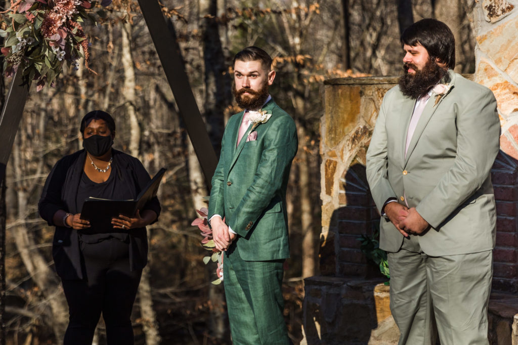 groom watching bride walk down aisle on airbnb wedding day in green suit during woodland chic wedding