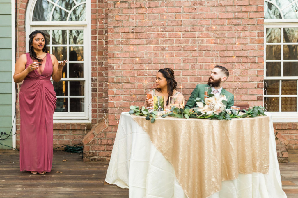 bridesmaid wearing pink dress giving toast at wedding reception