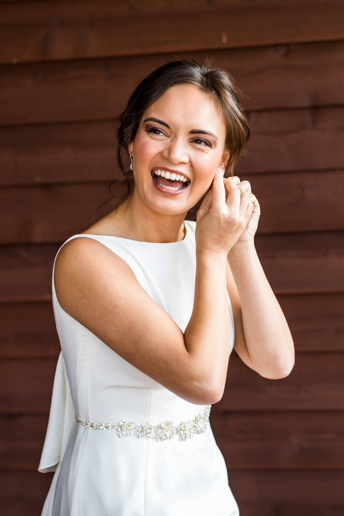 bride putting on earrings and laughing on wedding day in Charlottesville