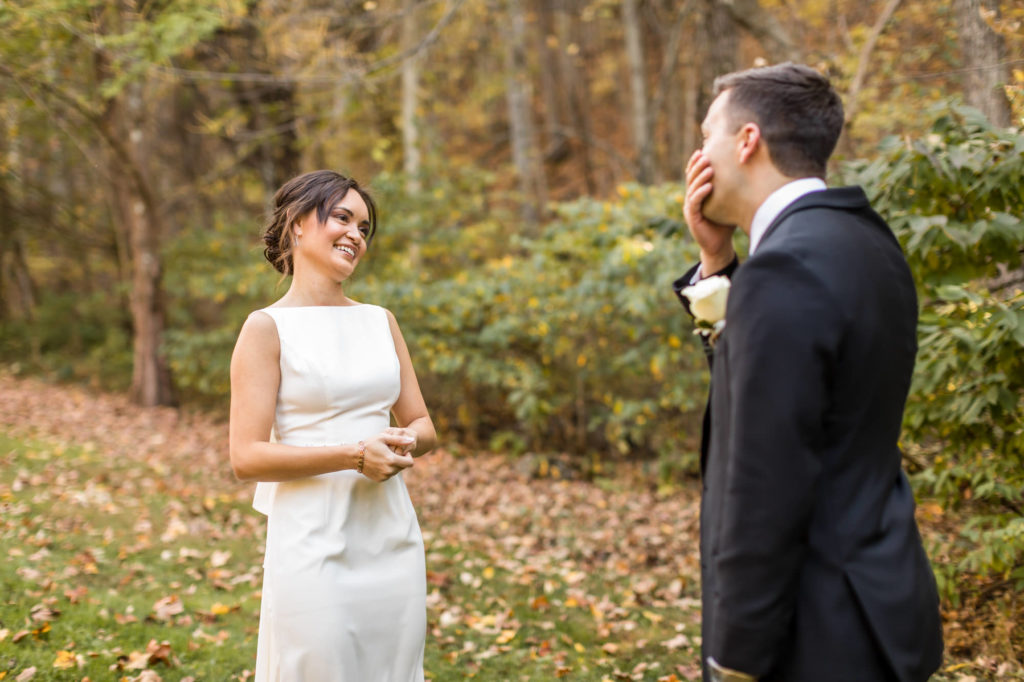 groom putting hand over mouth after seeing bride for first time on wedding day