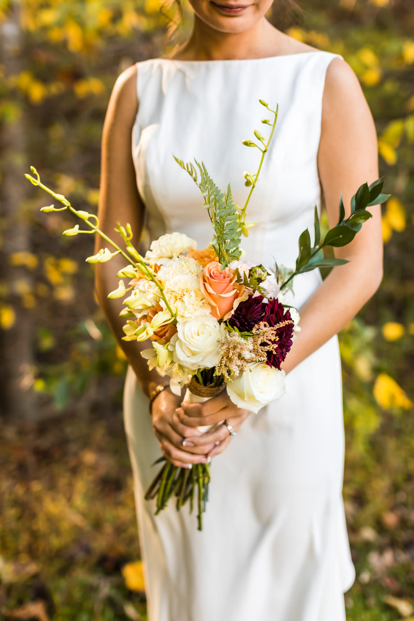bride holding bridal bouquet with florals of white, yellow, green and peach flowers